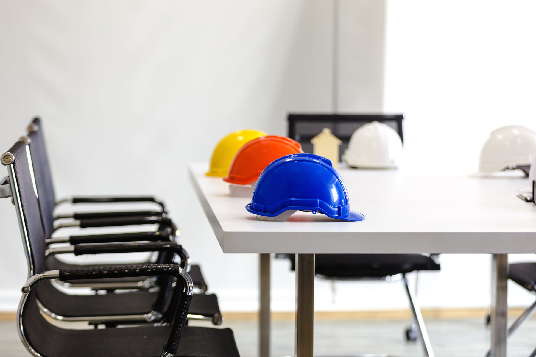 Bauarbeiterhelme auf Tisch vor dem Stühle Stehen