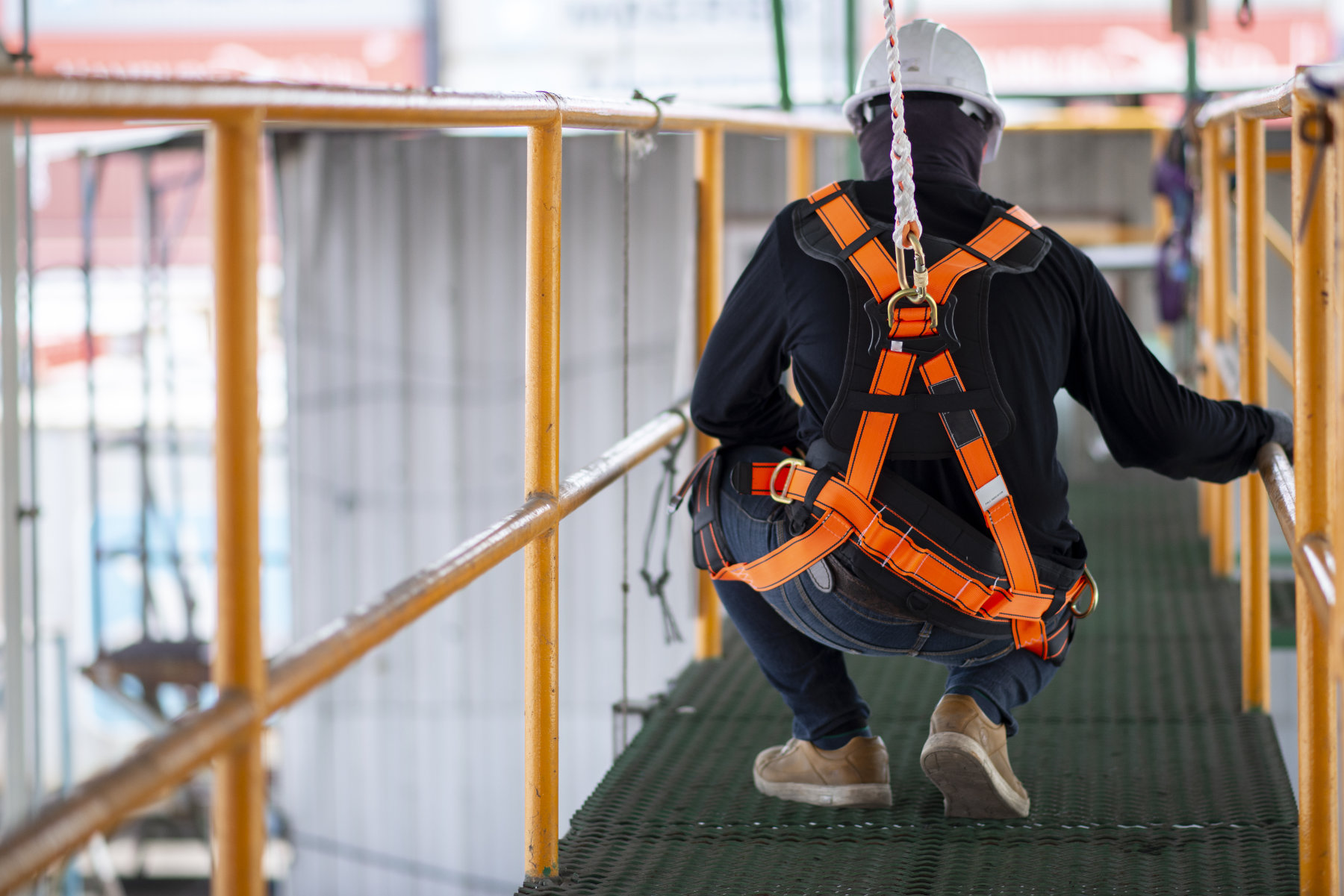 Mann mit Bauarbeiterhelm ist an Seil befestigt